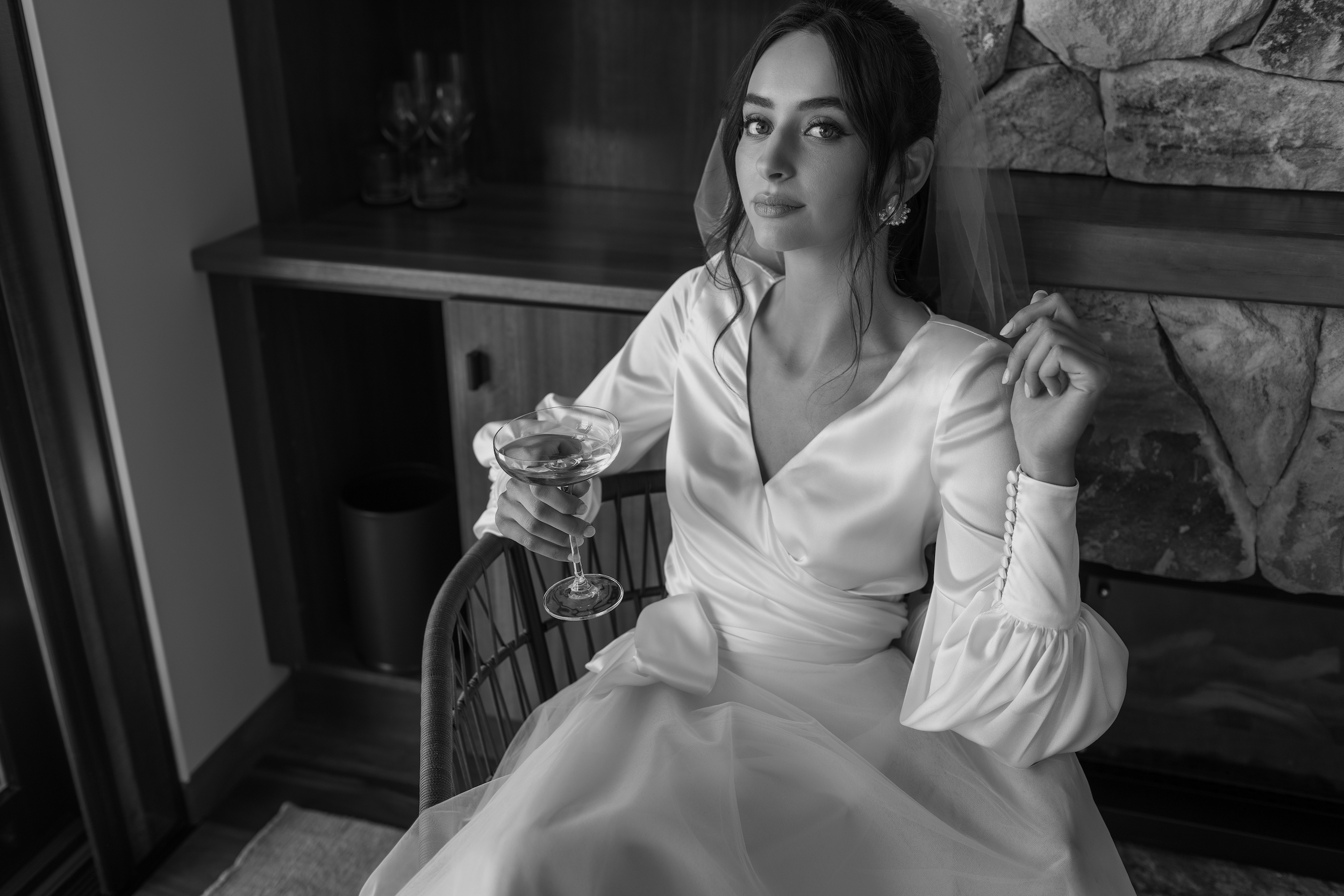 Wedding dress styles - Model sitting in chair in front of fireplace wearing Lydie silk wrap top and Odette skirt