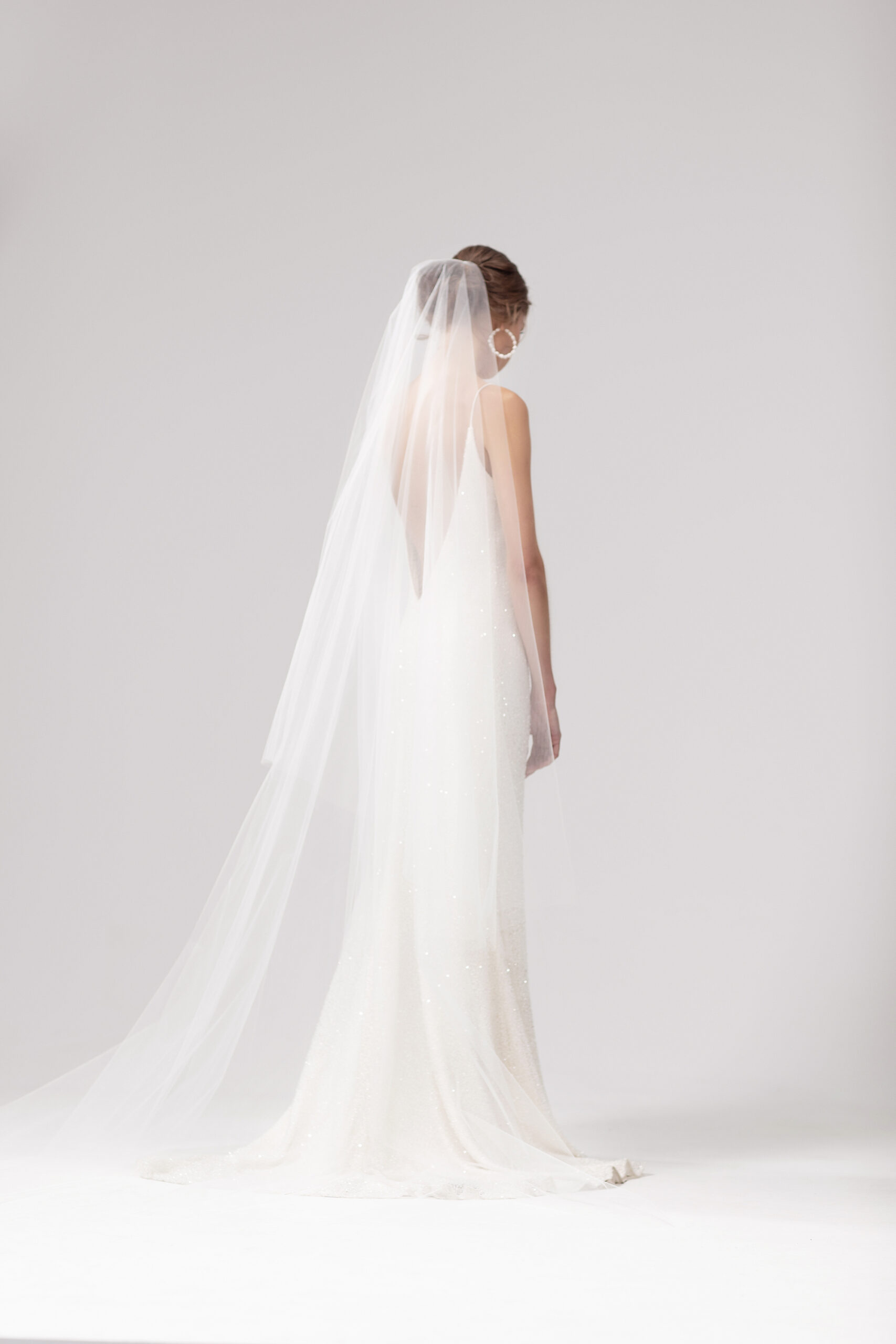 Back view of model wearing the Cher veil with both tiers at the back. Cher is a two-tier blusher style veil 2.5m long with a raw edge.
