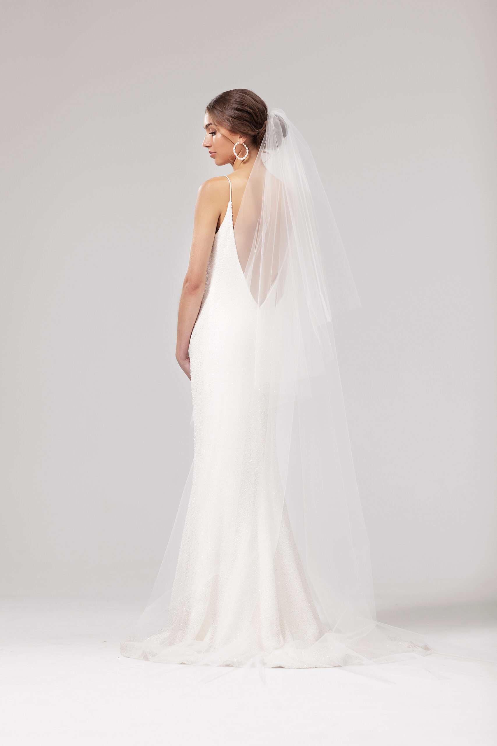 Back/side view of model wearing the Joy veil with both tiers sitting at the back. Joy is a two-tier 2.5m blusher style veil with a raw edge.