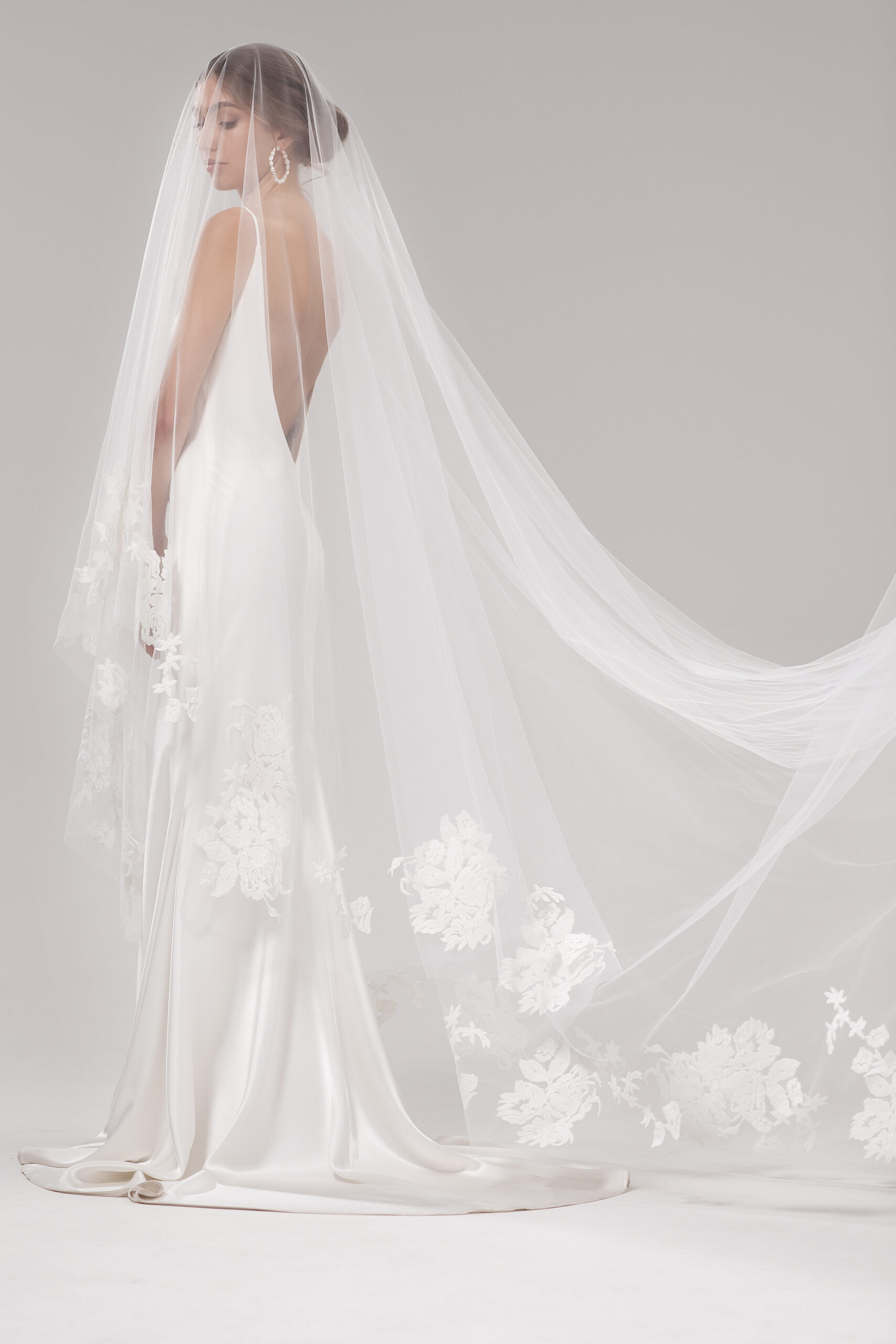 Side view of model wearing the Mayfair veil blusher style over the face. Mayfair is a two-tier 2.5m veil with delicate floral embroidery around the edge.