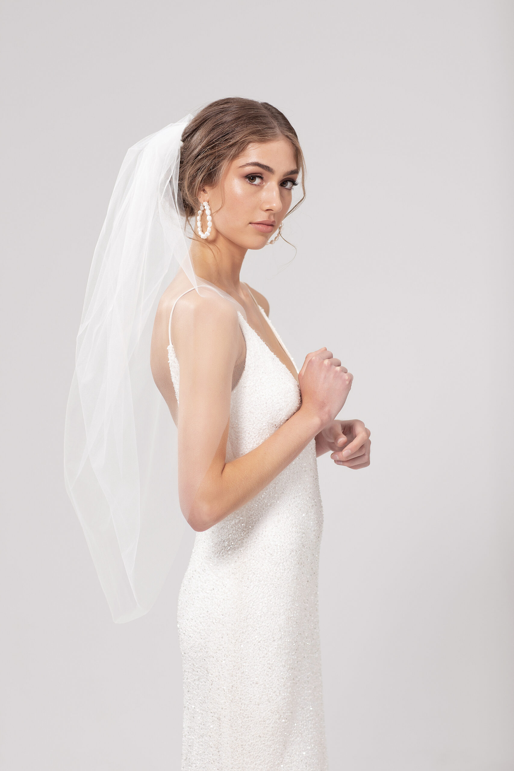 Side view of model wearing Pia, a single layer 95cm tulip style veil.