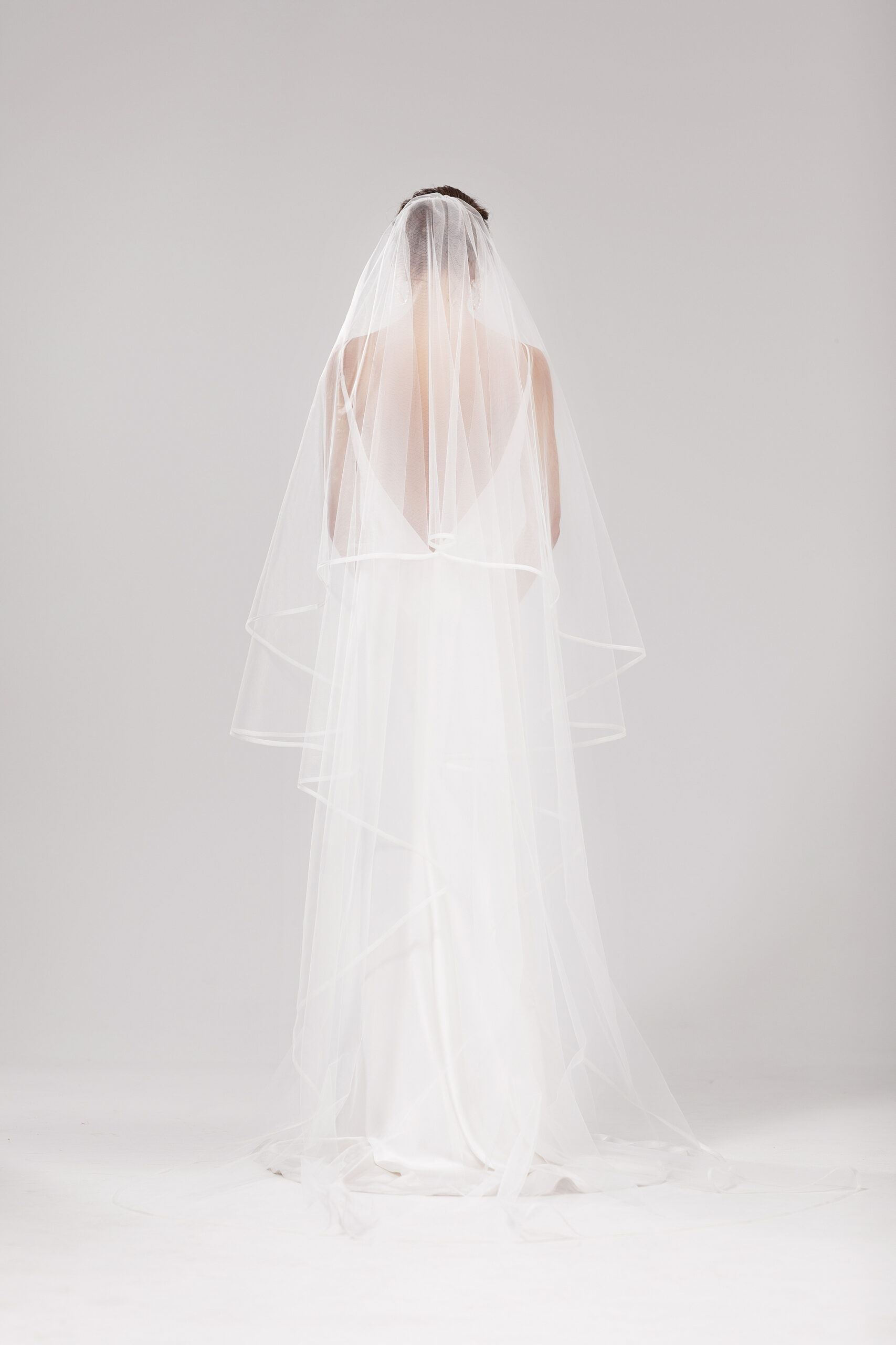 Back view of model wearing Snow in two tiers behind head. Snow is a 2.5m two-tier blusher style veil with an organza binding on the edge.