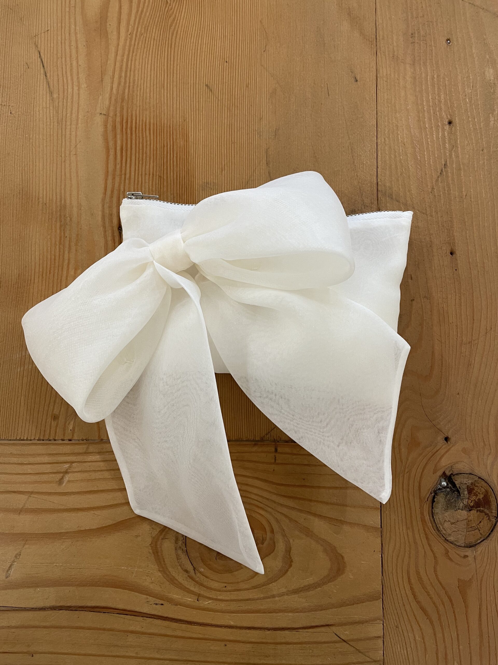 Bijou- a rectangle clutch in organza, with a large bow on the front and silver zip.