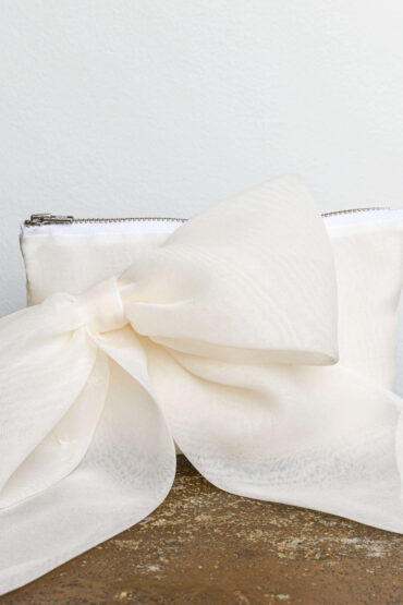 A classic rectangle shaped clutch in organza, featuring an elegant bow detail on the front.