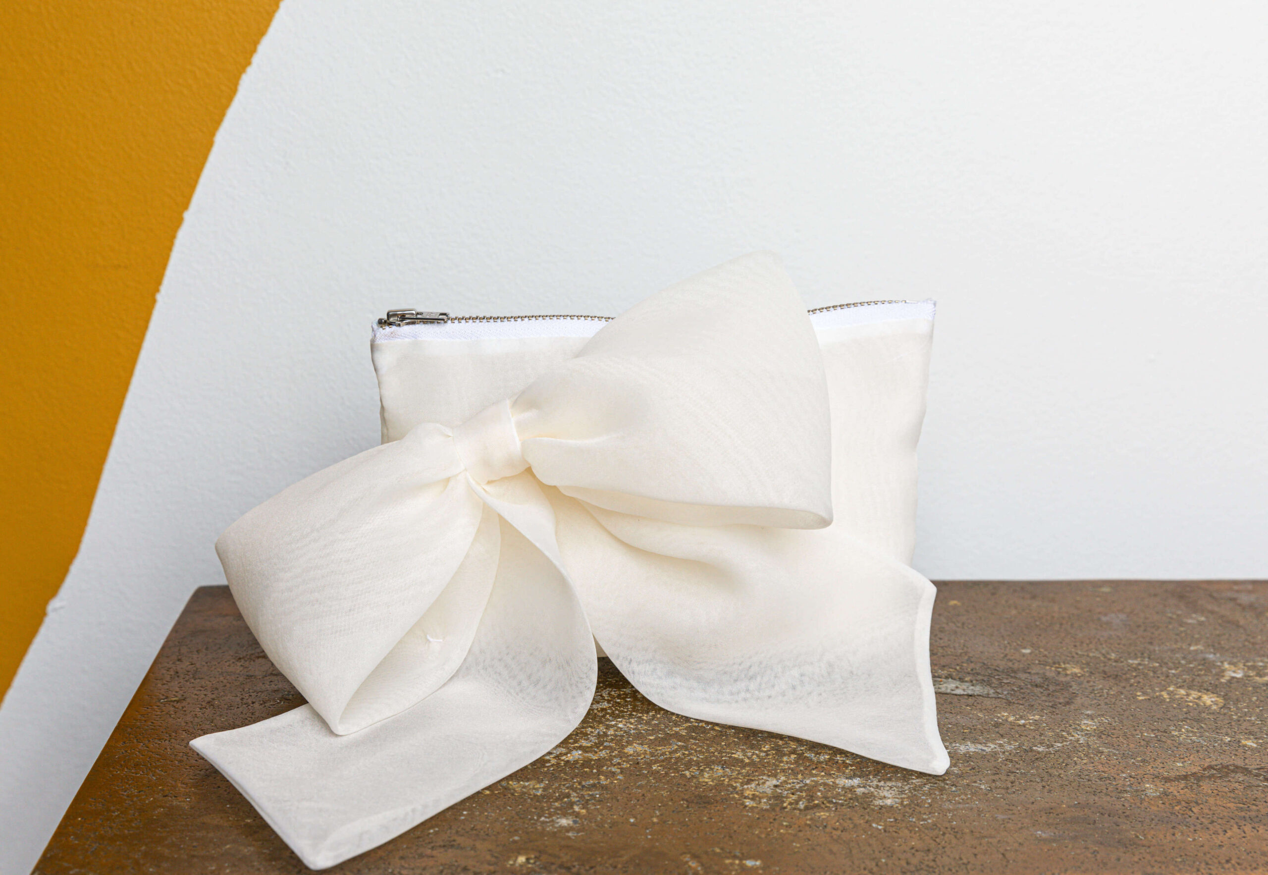 A classic rectangle shaped clutch in organza, featuring an elegant bow detail on the front.