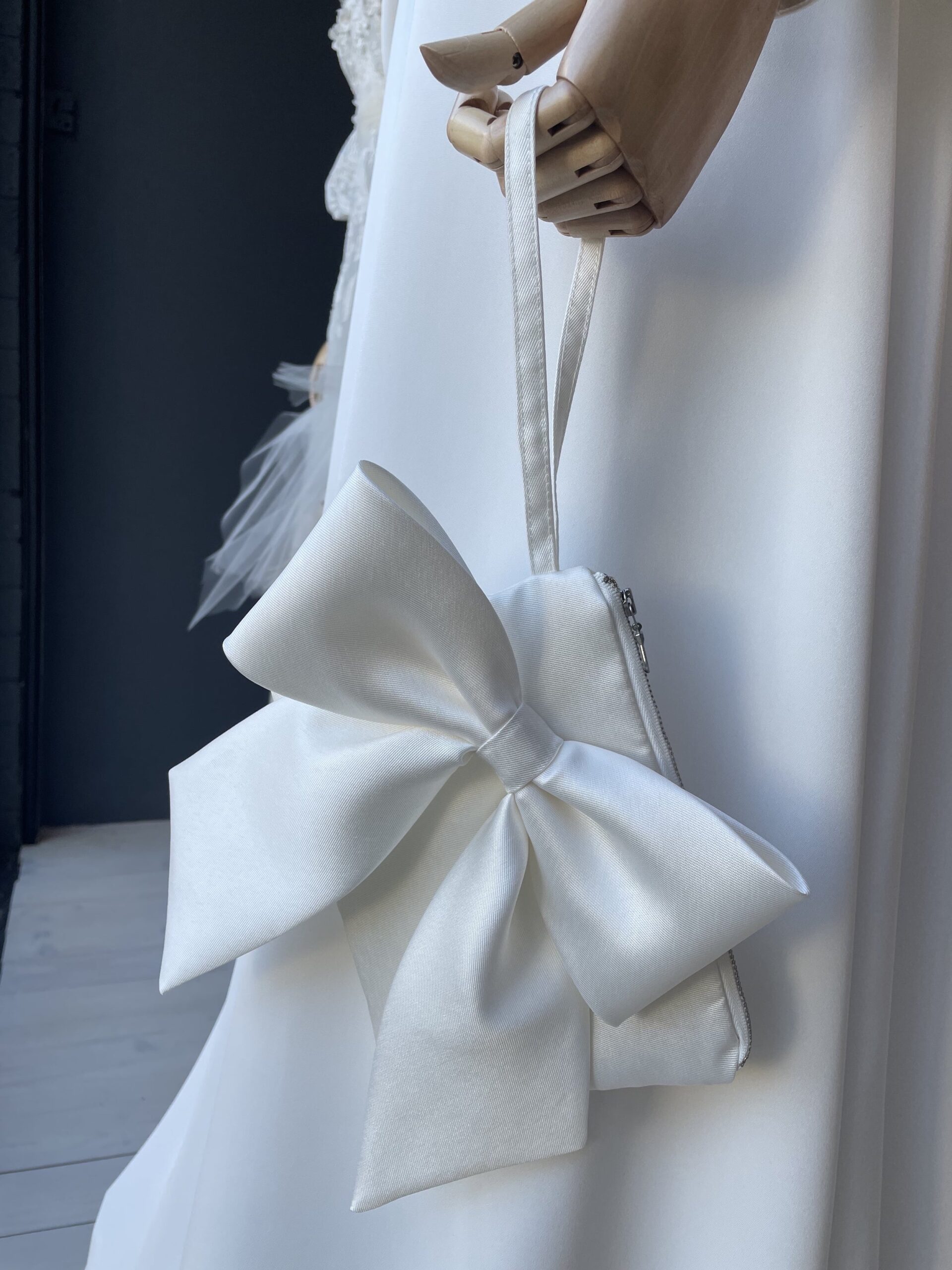 Mannequin with wooden hands in ivory satin gown holding Mica bag in Twill by the wrist strap