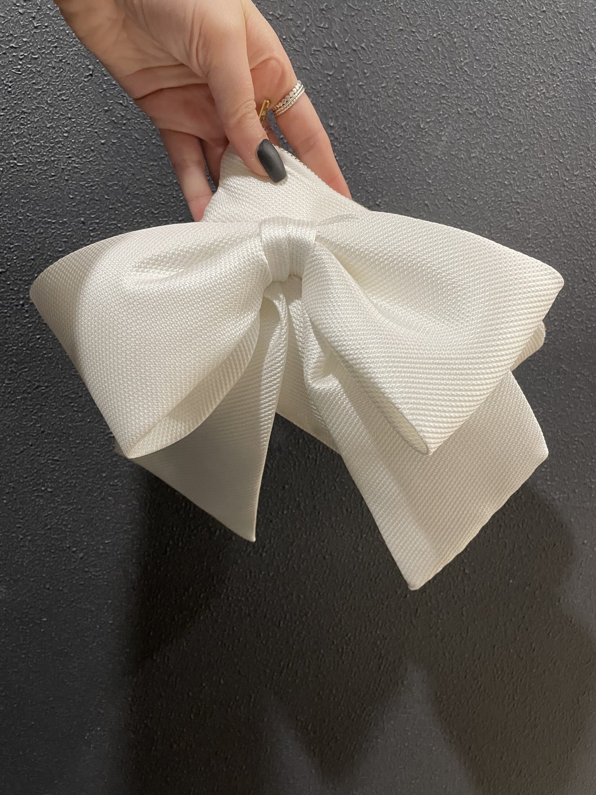 Mica - a rectangle clutch in a thick twill fabric, with a large bow on the front and gold zip.