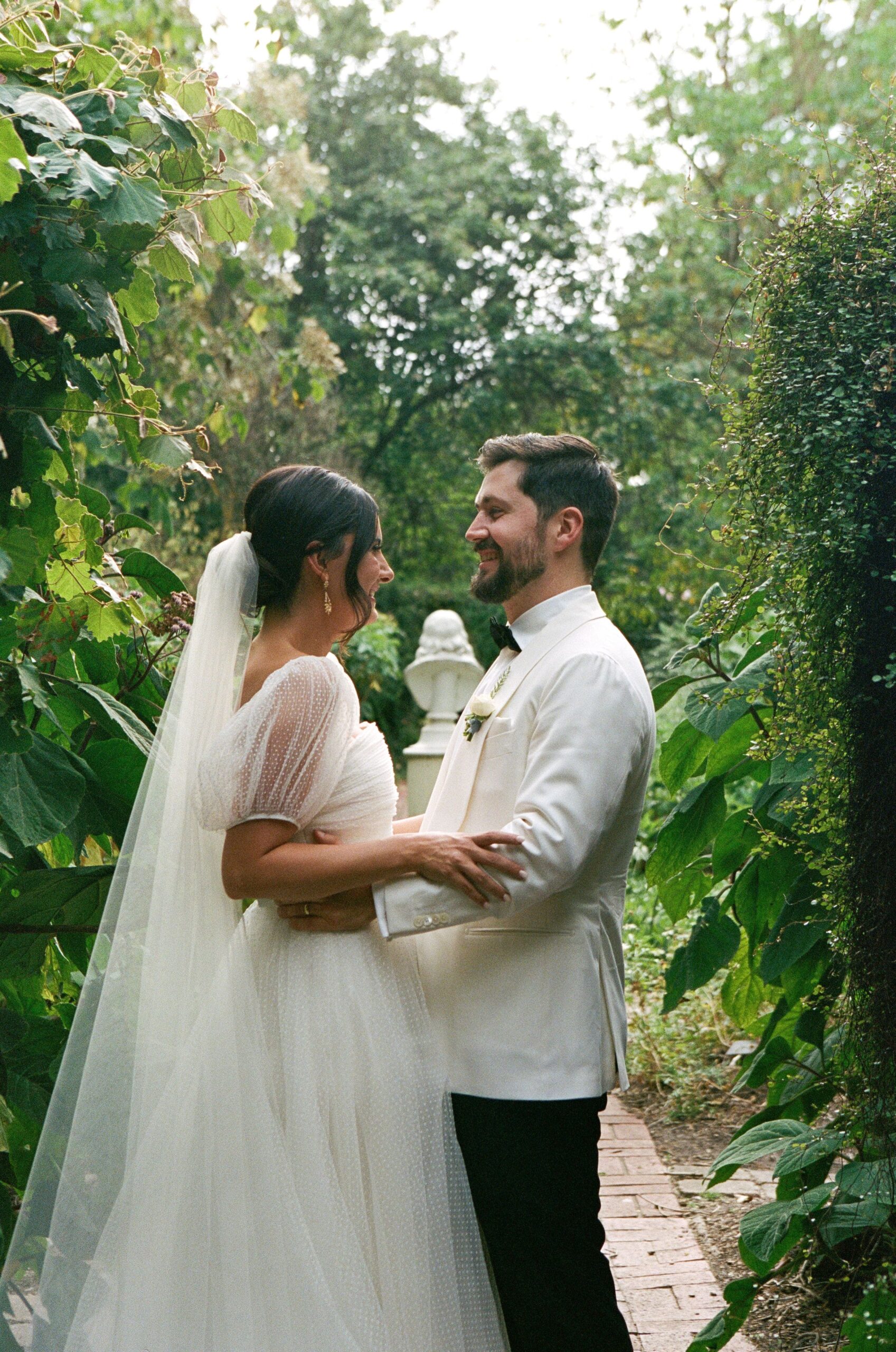 Maddy and Jason holding each other amongst the backdrop of greenery of the botanical gardens