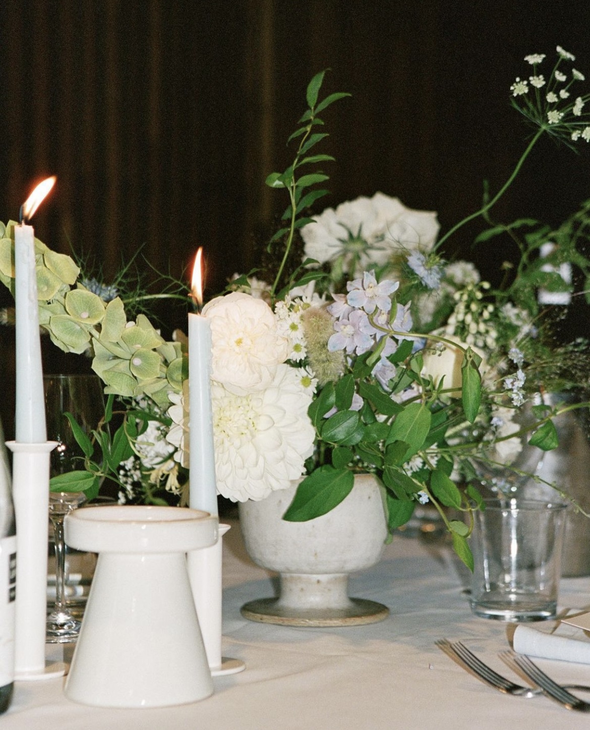 Reception table decor (flowers, white taper candles, white vases and silver cutlery)