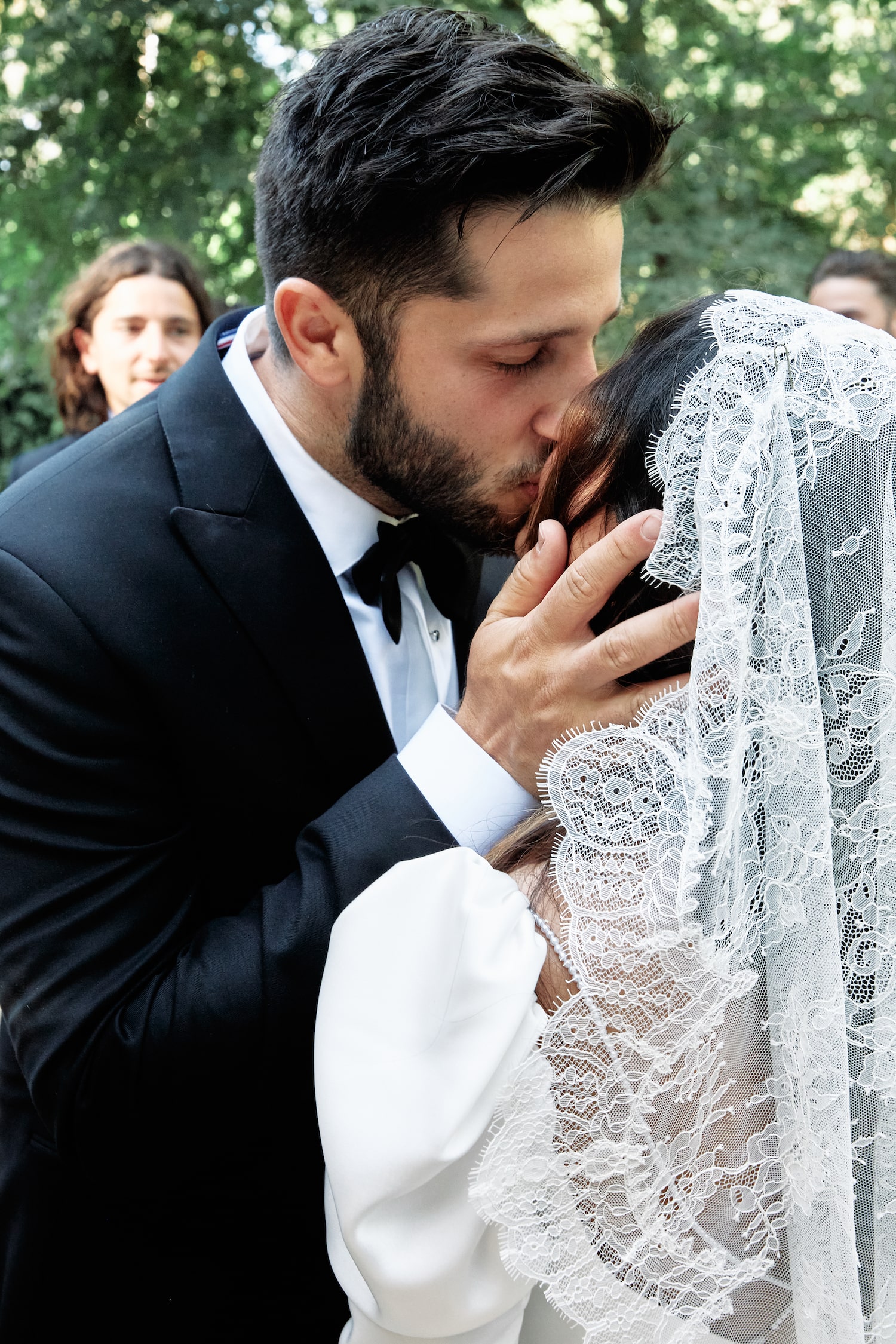 Groom holding brides face as they share a kiss