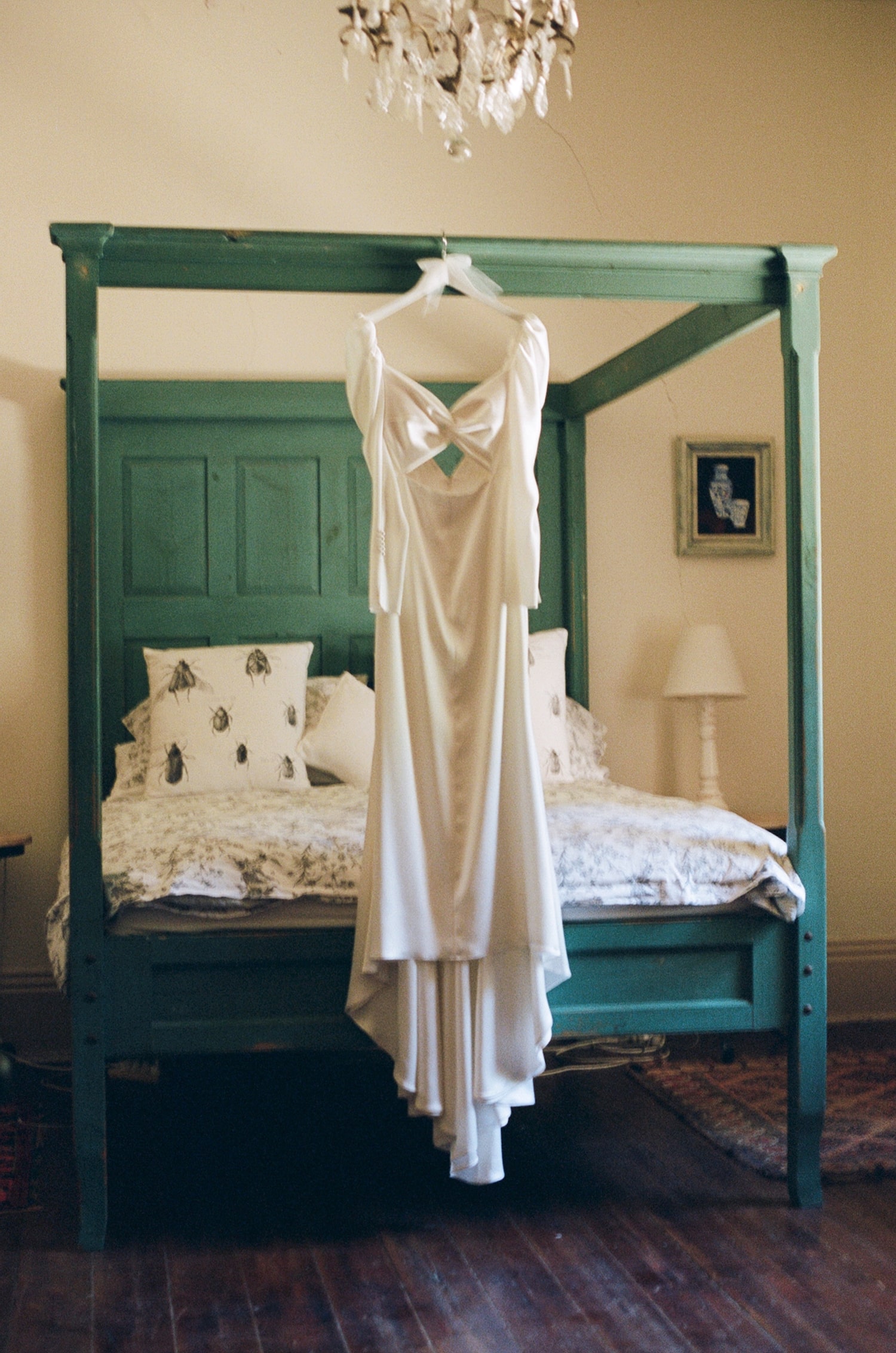 Brides dress hanging from the top of a four poster bed