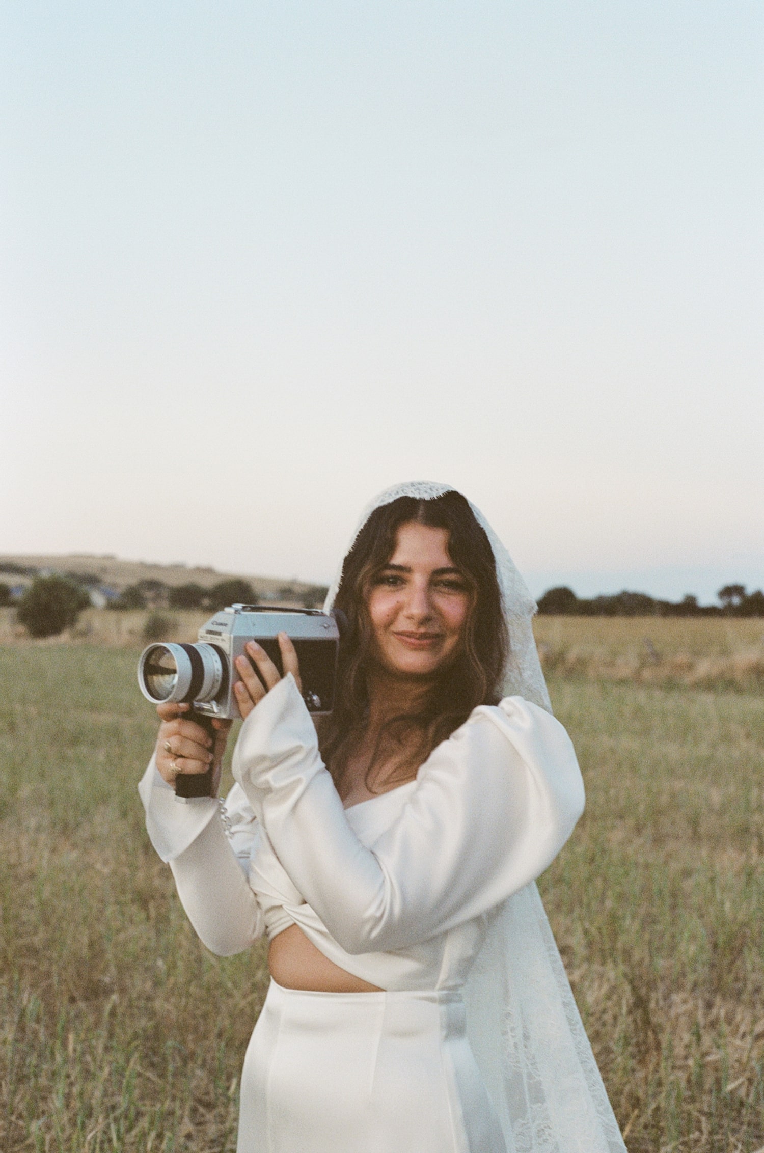 Bride in a field holding an old camera