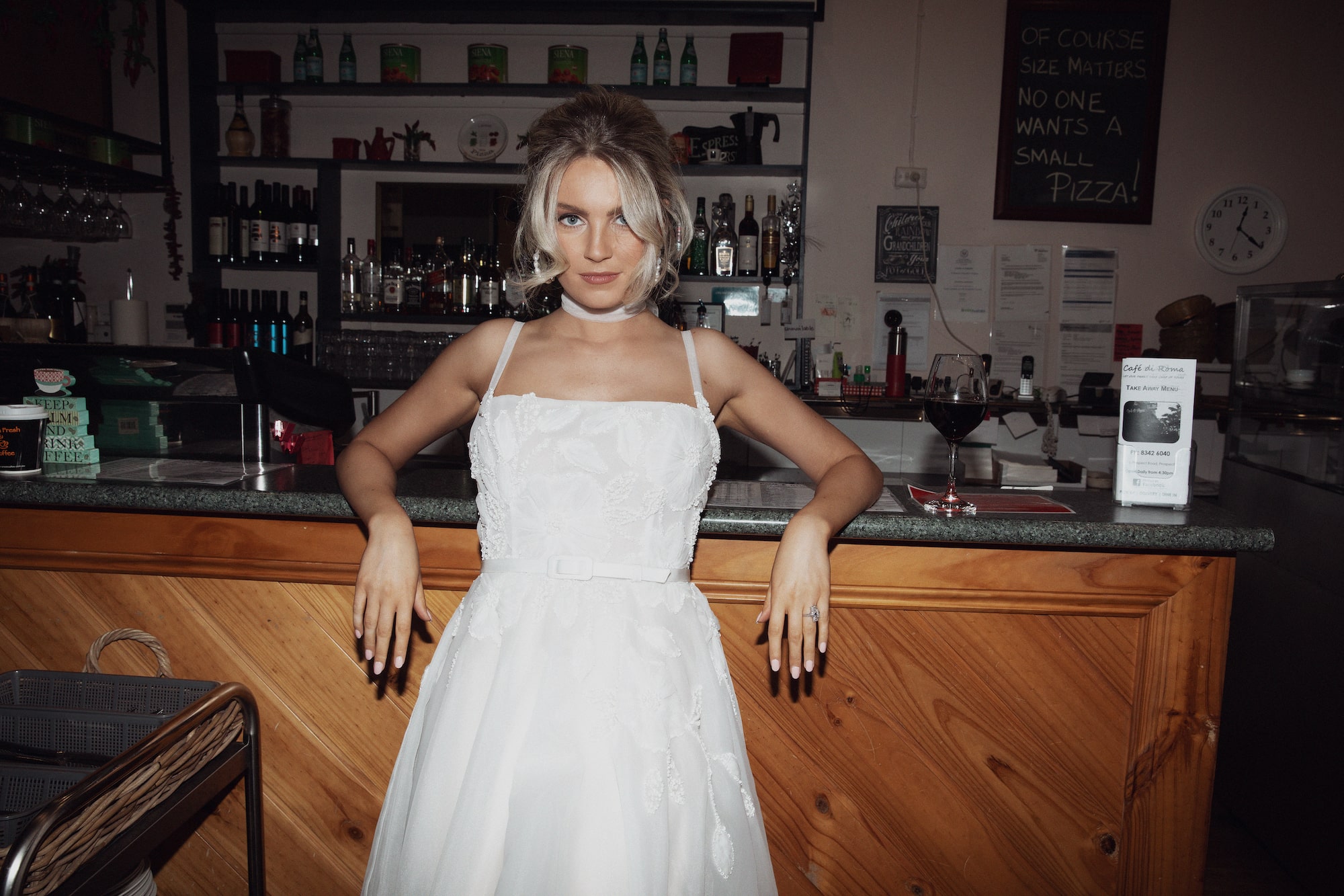 Model leaning against bar counter in Italian cafe wearing the Fiorella gown.