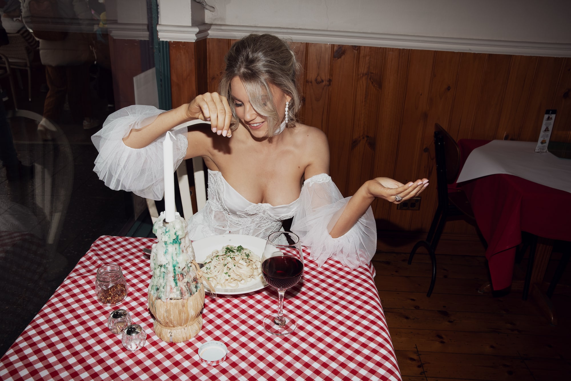 Model posing sprinkling salt onto pasta seated at a table in an italian cafe