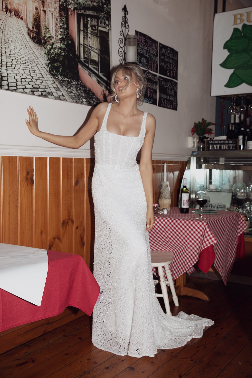 Model posing against wall in Italian cafe wearing the Ornella gown.
