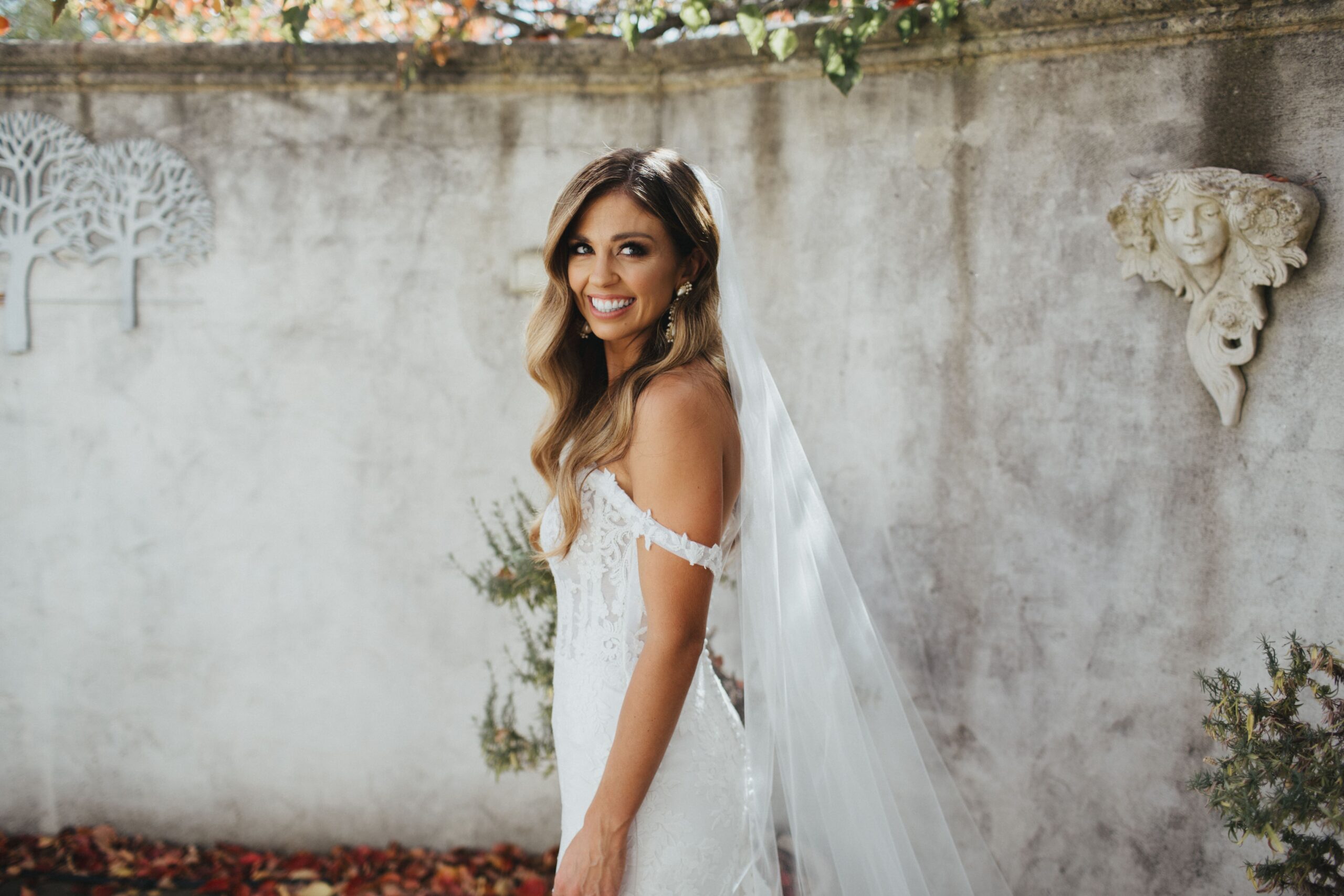 Bride standing in front of concrete wall looking into camera