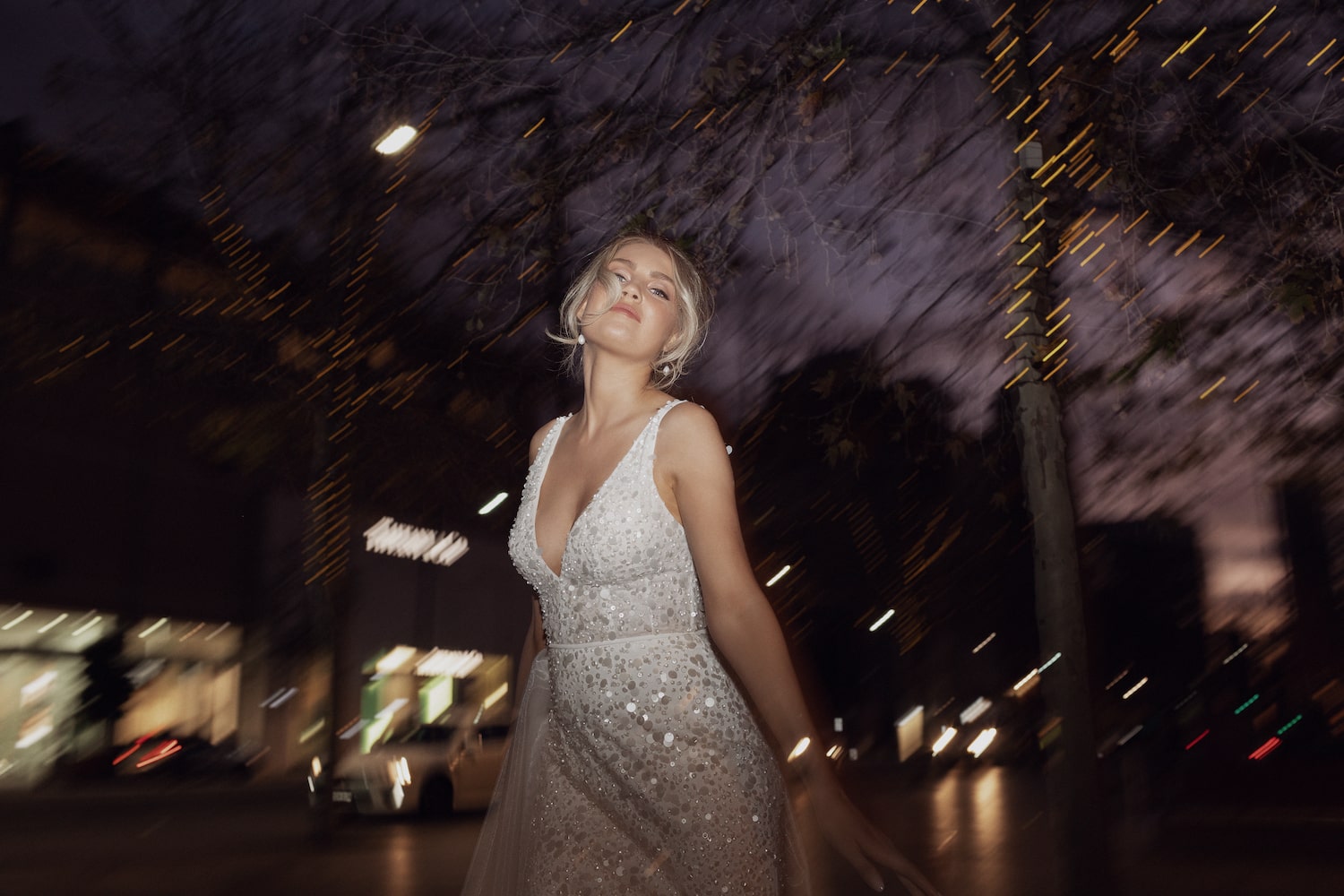 Model posing on city sidewalk at night