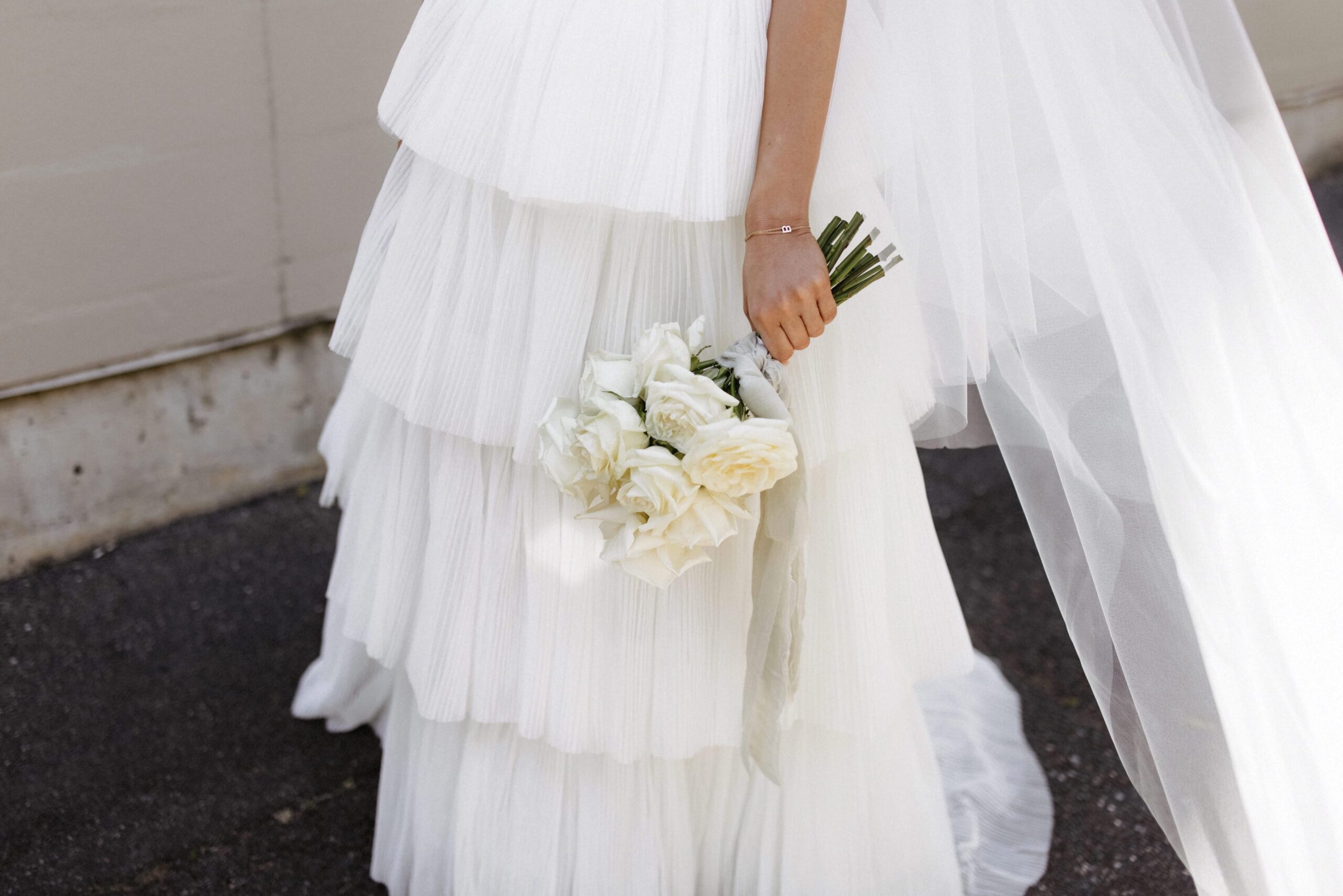 A close up image of Bethany's full tiered skirt and white bouquet.