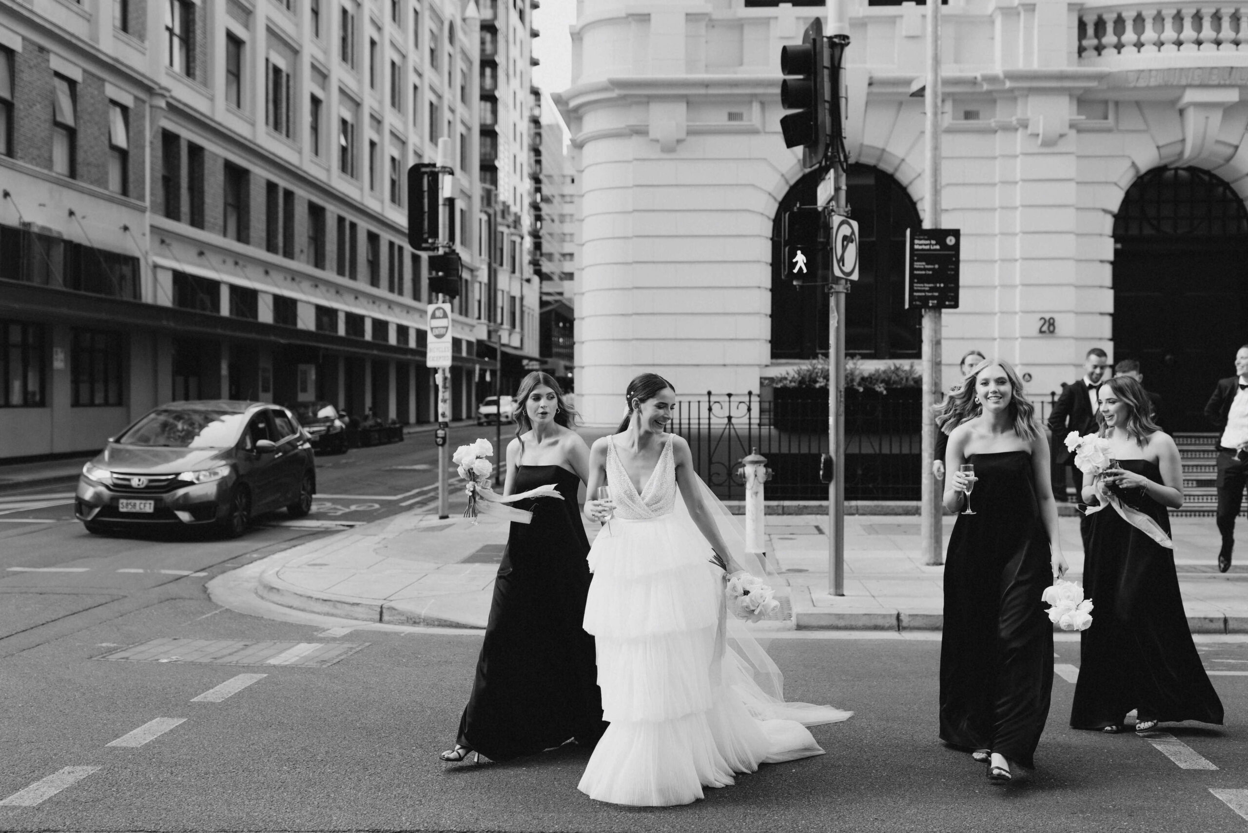 Bethany and bridesmaids walking across a city intersection