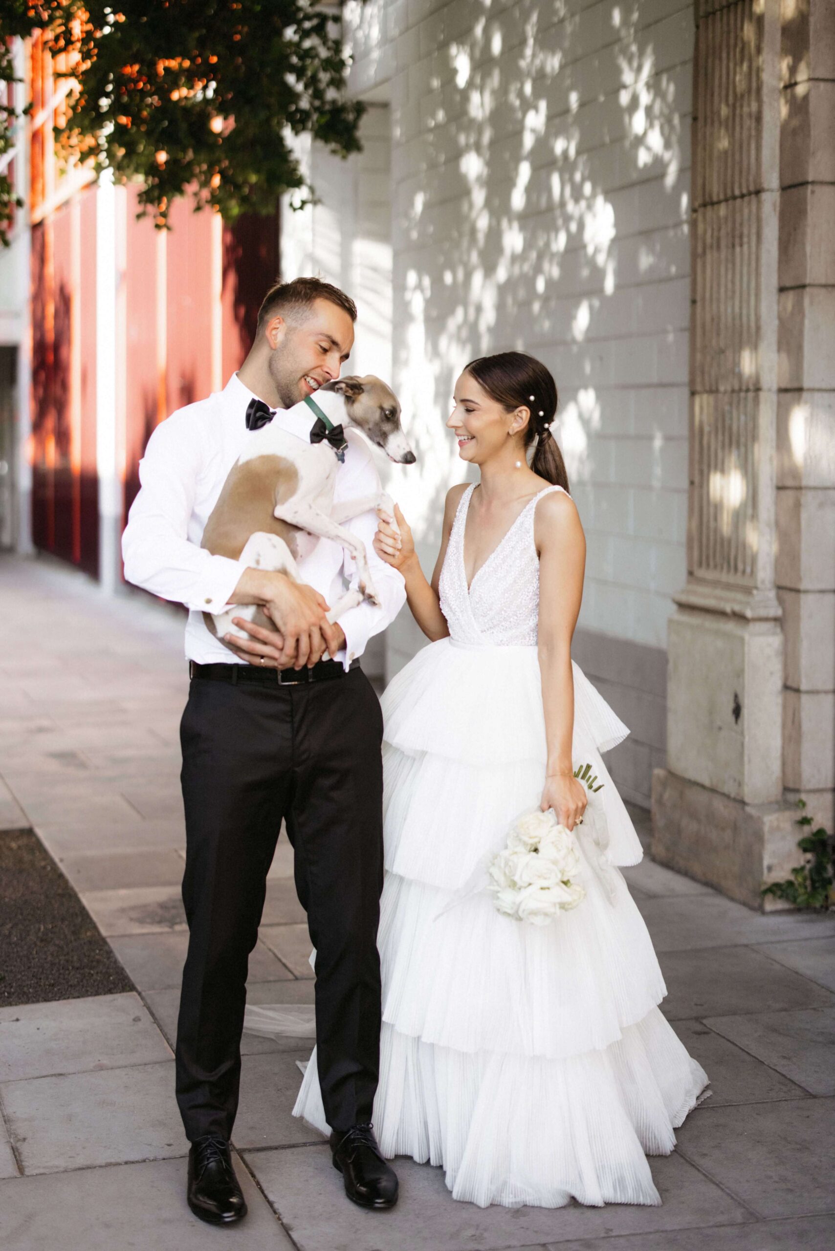 Bethany and Daniel holding a dog wearing a bow tie