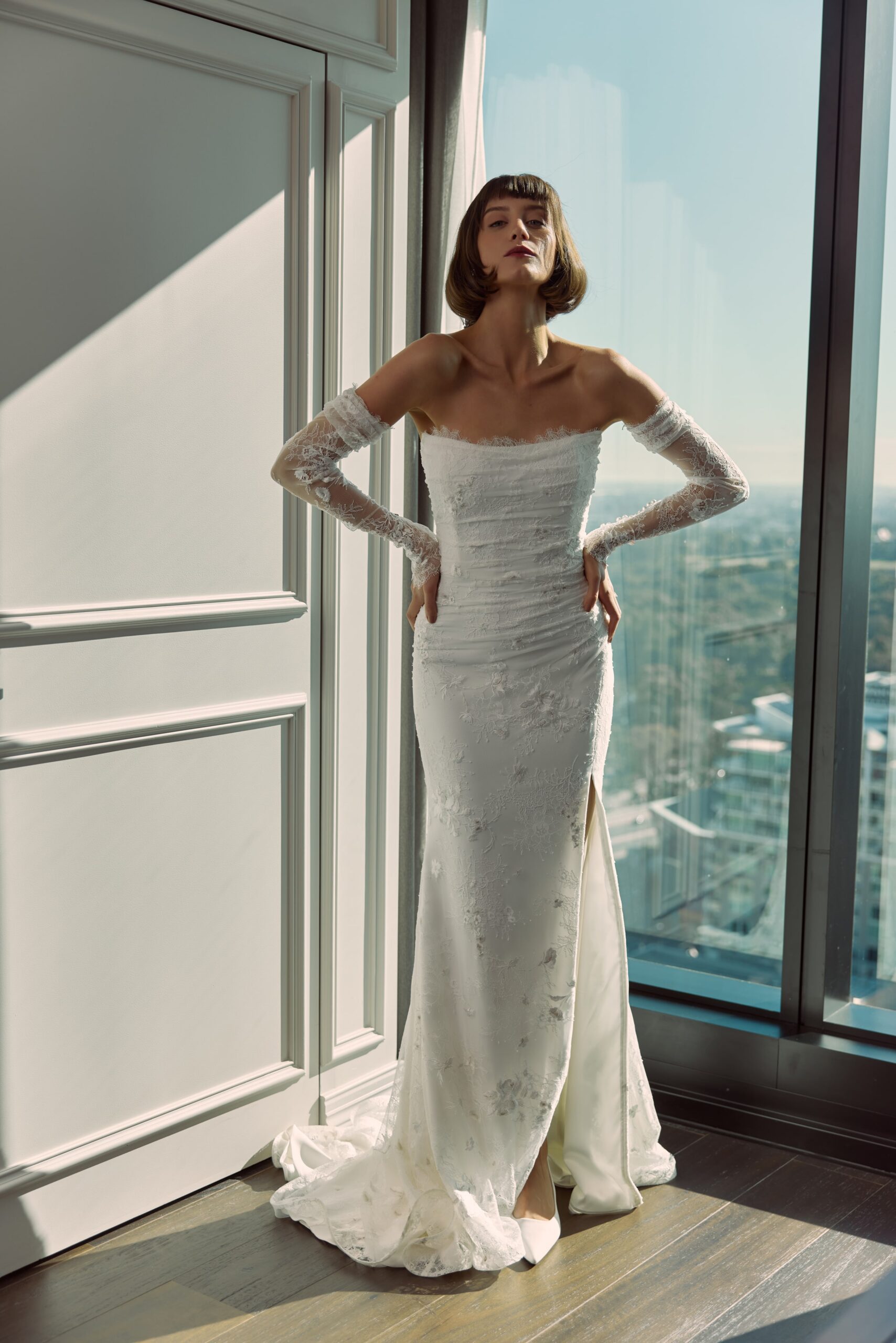 Colette - a strapless soft mermaid gown with a rouched lace overlay and detached sheer sleeves.