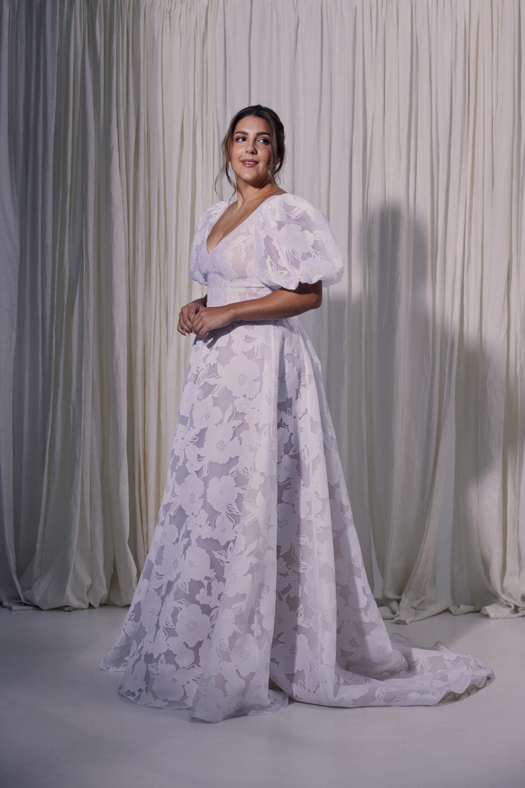 Flora is a devorè linen-rayon blend A-line gown with a V-neckline, all-over floral detail and puff sleeves.