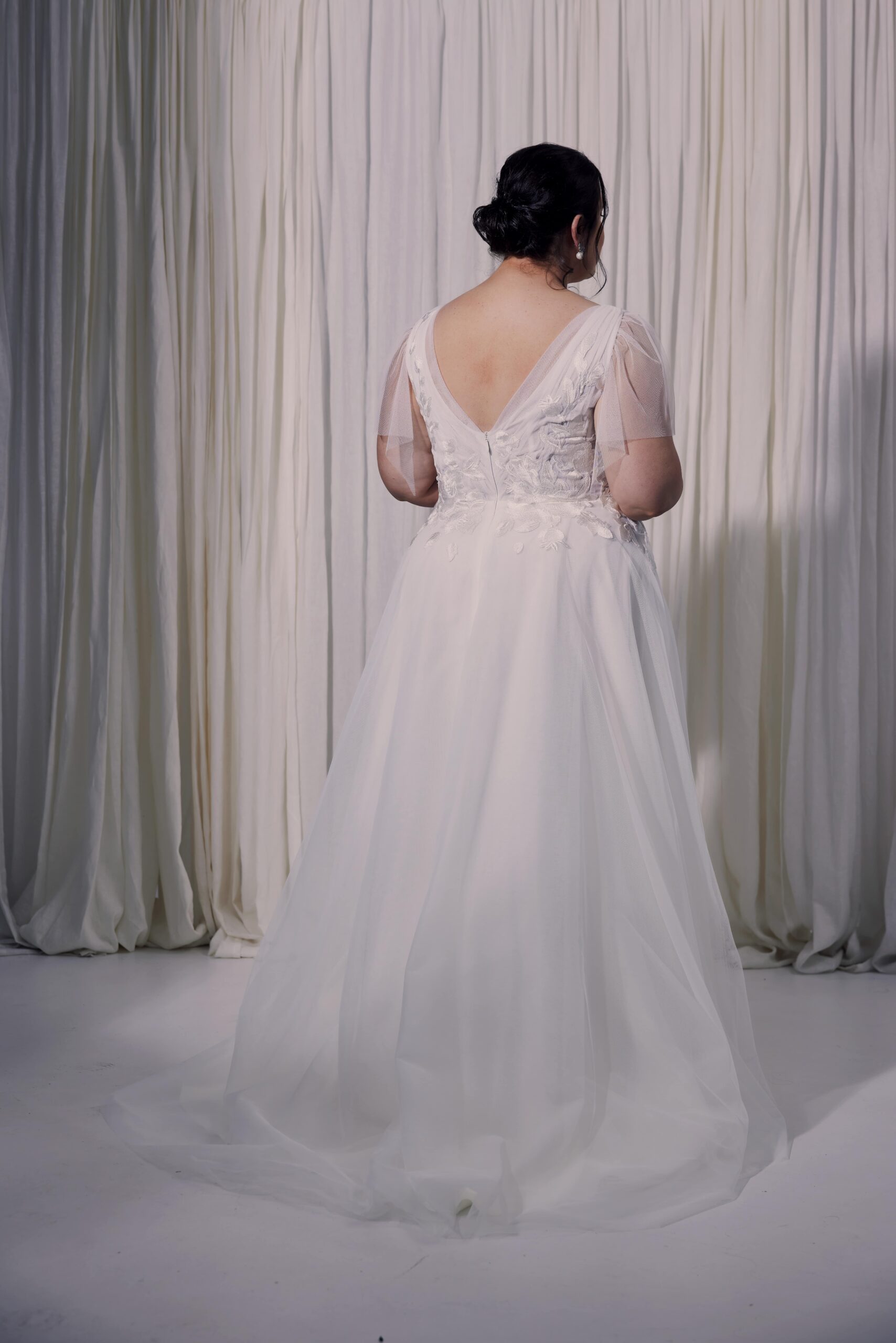 The Ella gown - a V-neck soft tulle gown with flutter sleeves and embroidered lace applique trailing into a soft flowing skirt.