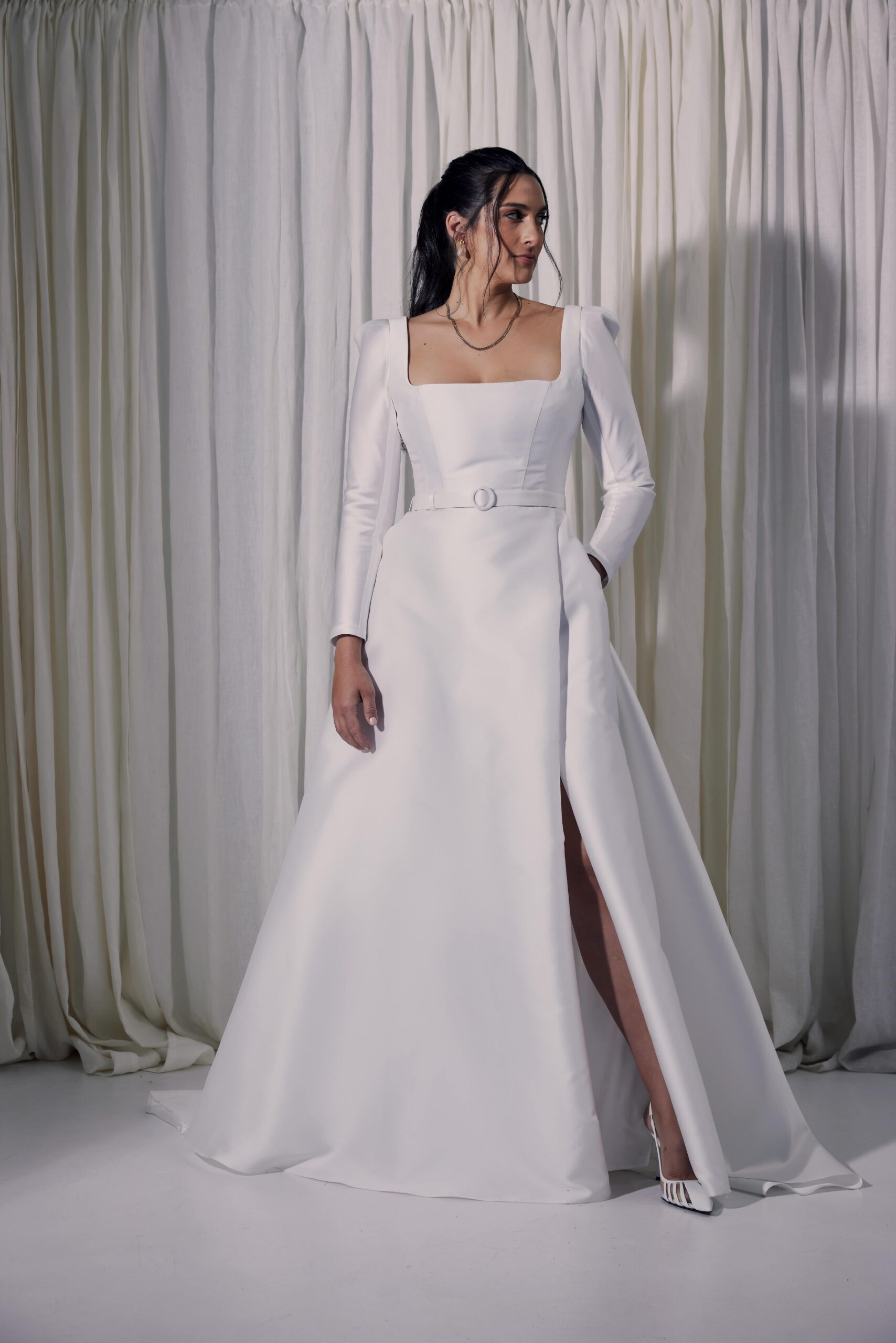 The Gianna gown - a contemporary ballgown cut from a silk mix mikado with a square neckline, tailored sleeves, a covered belt at the waist and a wrap split.