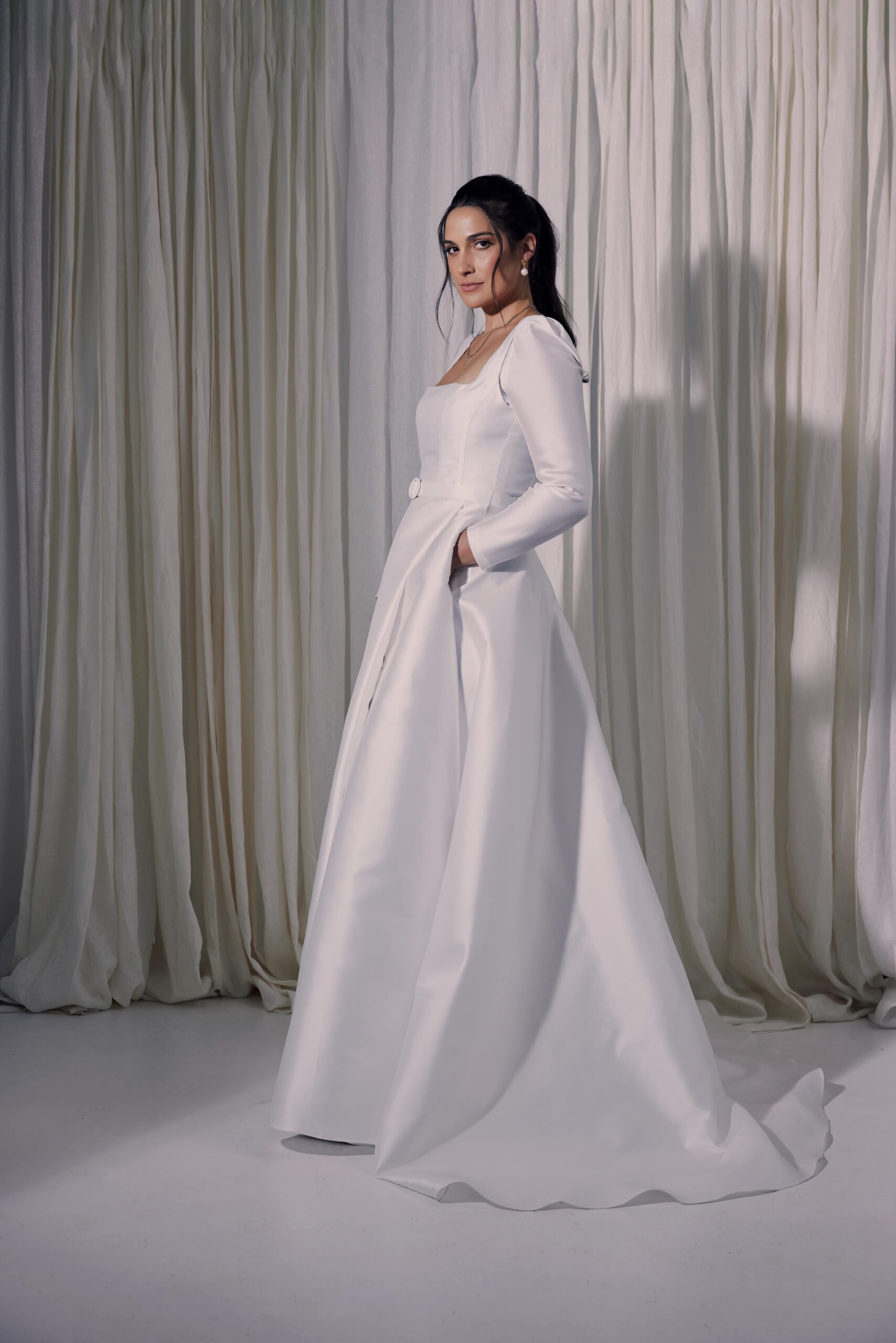 The Gianna gown - a contemporary ballgown cut from a silk mix mikado with a square neckline, tailored sleeves, a covered belt at the waist and a wrap split.