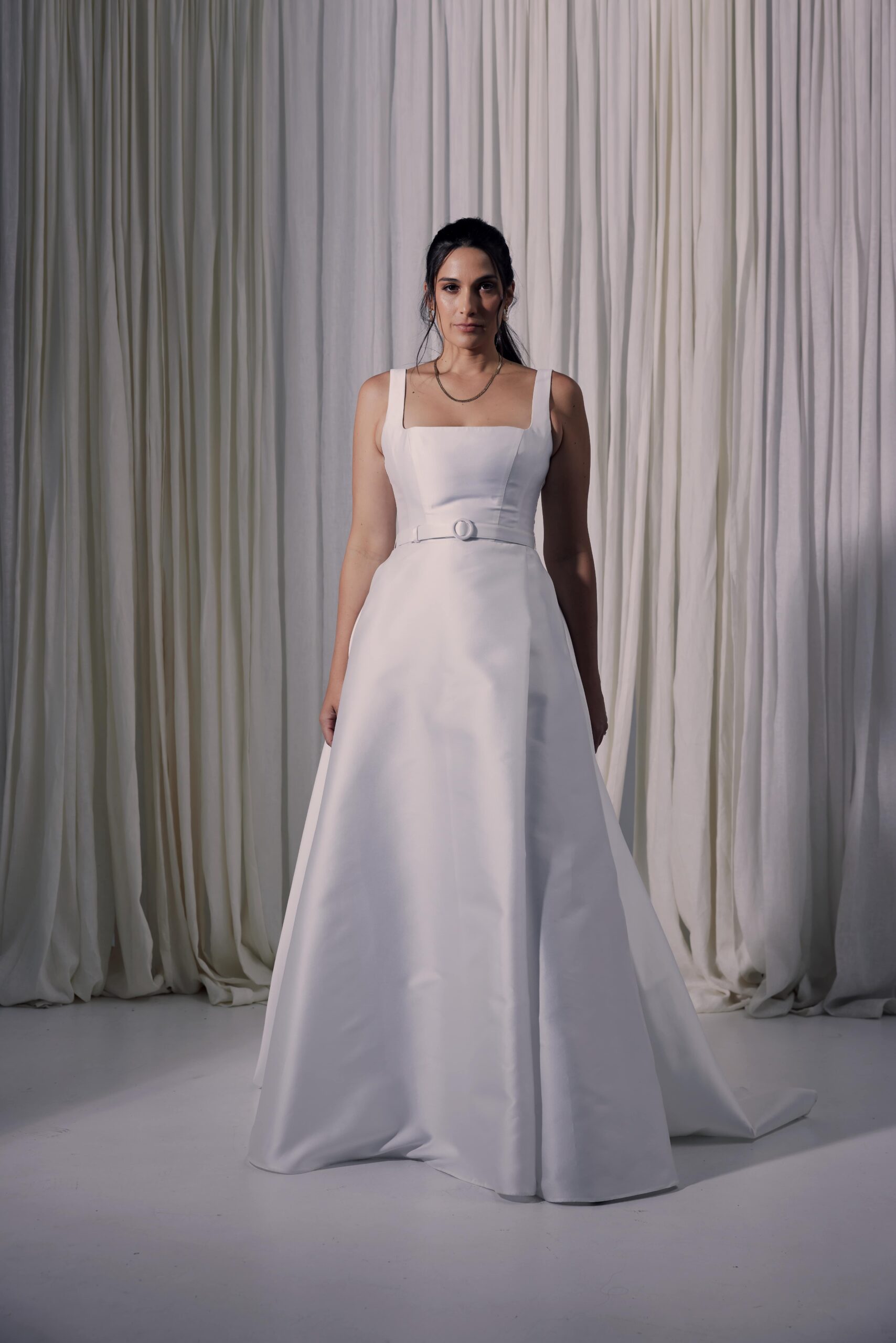 The Gianna gown - a contemporary ballgown cut from a silk mix mikado with a square neckline, a covered belt at the waist and a wrap split.