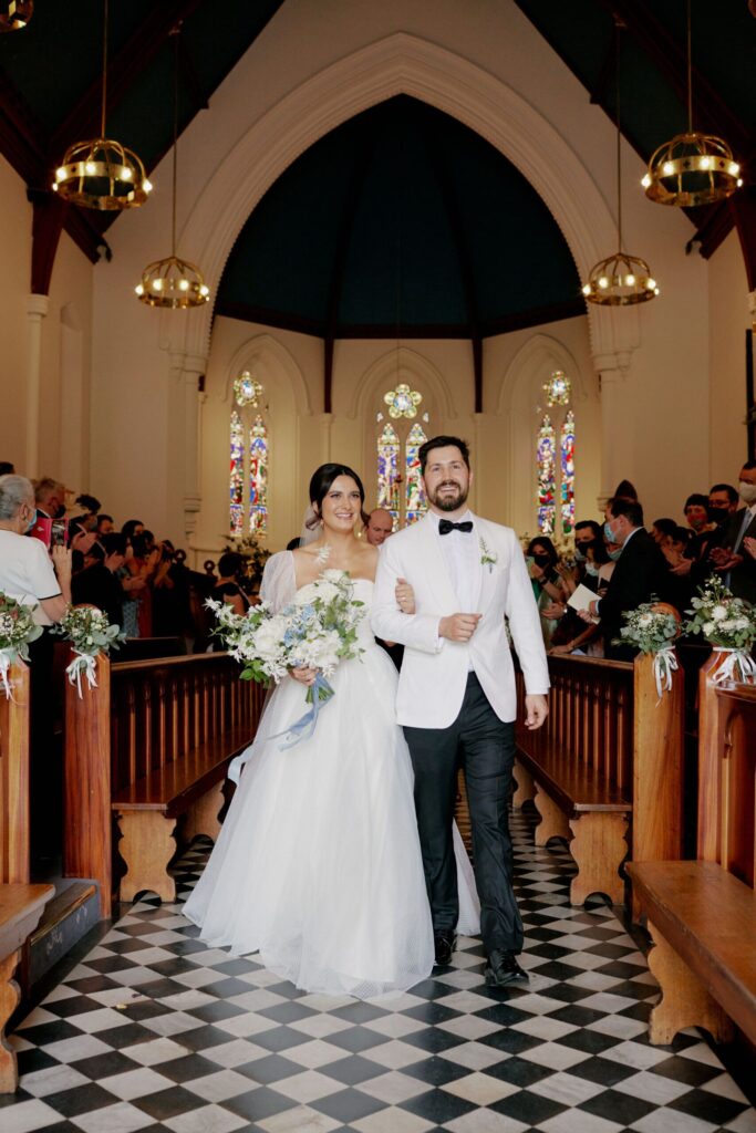 Maddy and Jason walking down the aisle arm in arm in the St Peters church