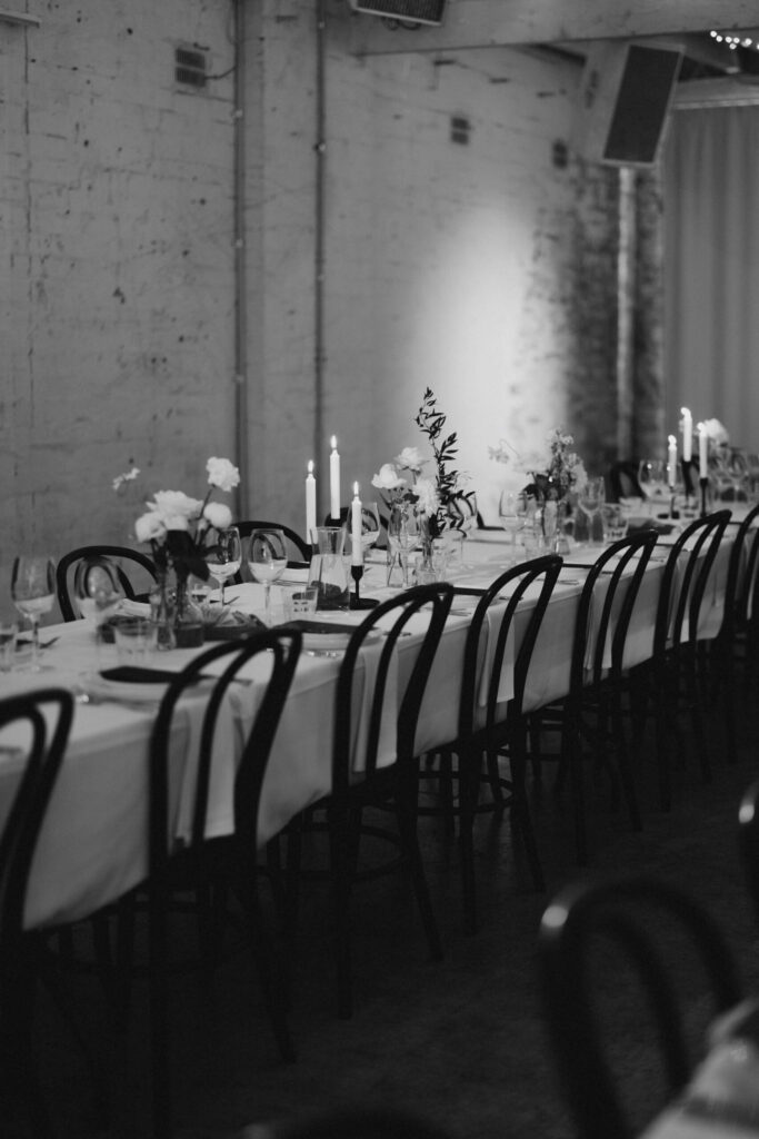 Reception table decor - wooden chairs, white tablescape with candles and flowers