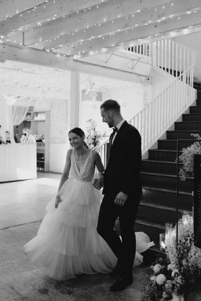 Bethany and Daniel hand in hand walking down a large staircase inside the rustic wedding venue