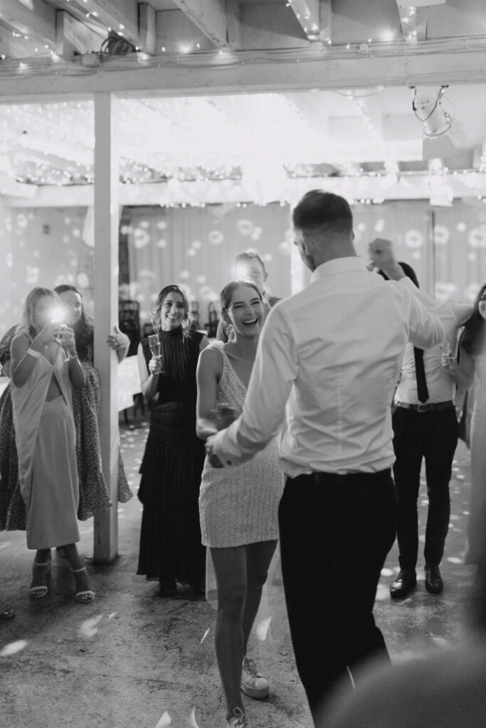 Bethany and Daniel dancing at the reception. Bethany has removed her tiered full skirt and is wearing the sparkly mini dress only.