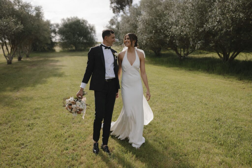 Olivia and Patrick walking arm in arm amongst grass and trees