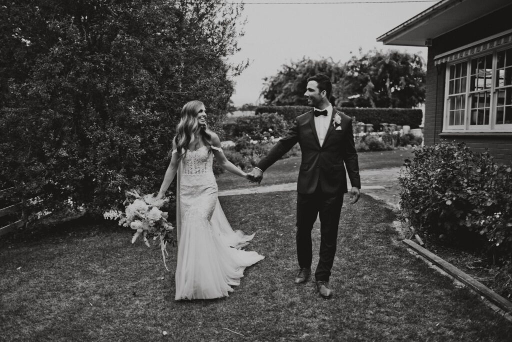 Couple walking hand in hand through a garden