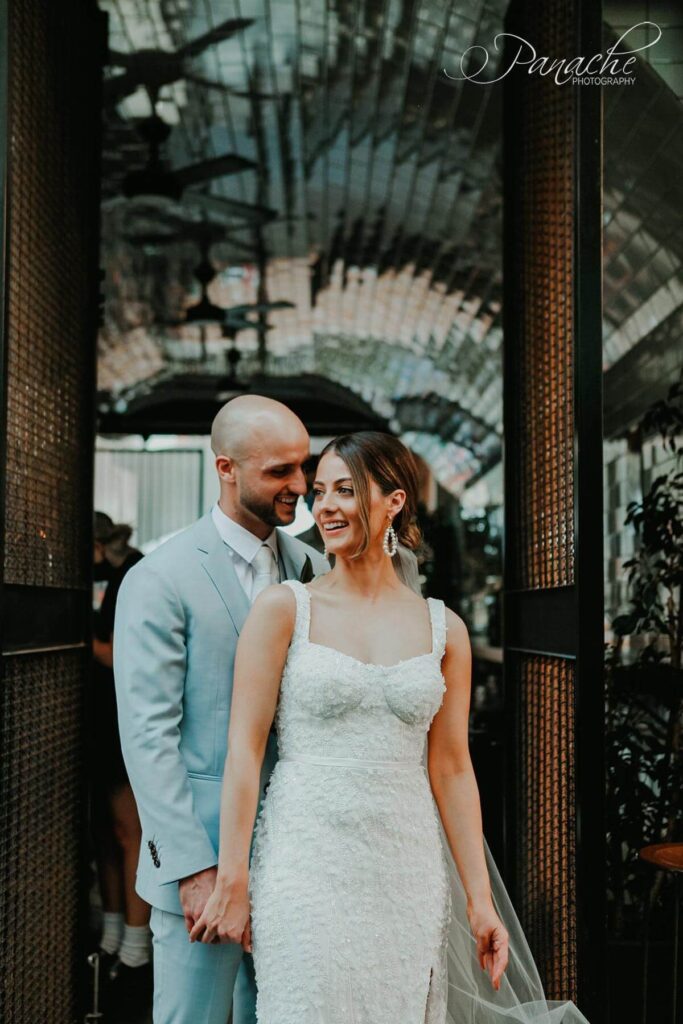 Cristiana and Jake standing in Peel street in the city. Cristiana is infront of Jake. Cristiana is wearing her gown without the sleeves.