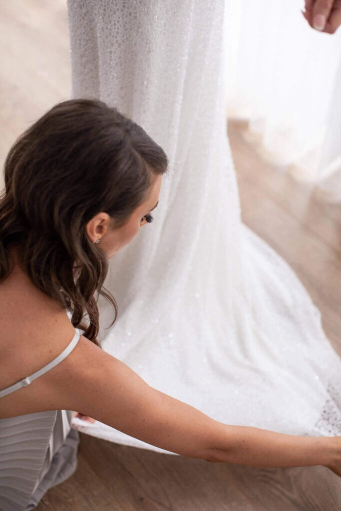 Alyssa's bridesmaid helping fan out the train of her gown