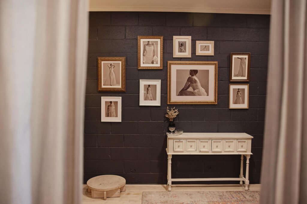 Wall of fitting room with framed photos from a bridal photoshoot on the wall